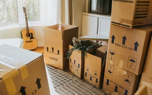 Fragile home items including a guitar and packed cardboard crates prepared for specialized fine art relocation